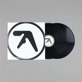A vinyl record partially pulled from its sleeve, shown on a plain gray background. The sleeve is white with a large black circular logo, and the record is black with a matching center label.